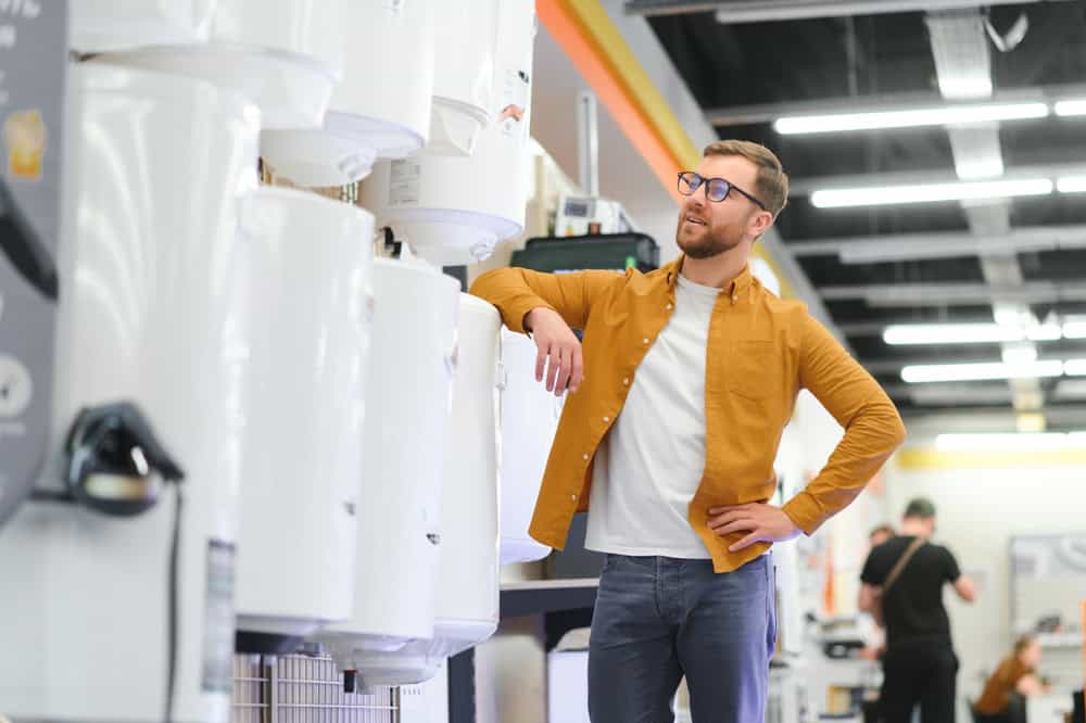 barbat care analizeaza oferta de boilere electrice verticale