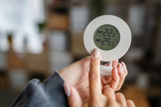femeie care seteaza temperatura unui termostat wireless